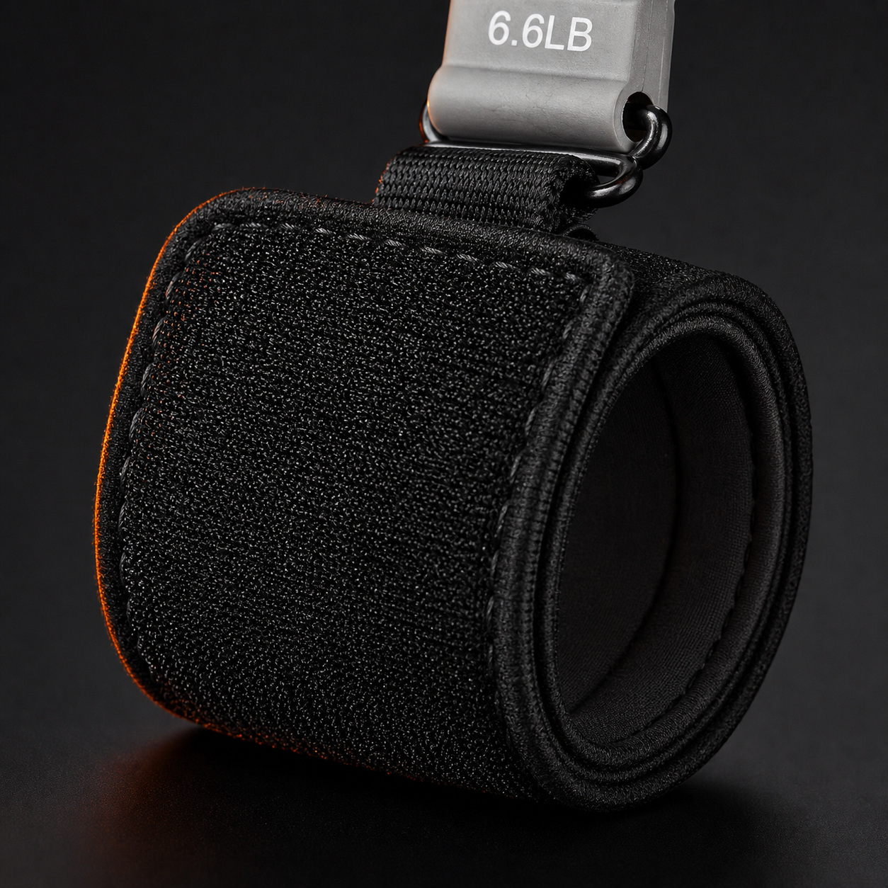 Close-up of the X-Grip Extensor adjustable velcro wrist strap and its metal attachment loop, with the 6.6 lb resistance block above